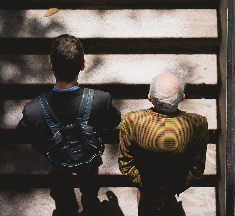 ένας νέος άνδρας δίπλα σε έναν ηλικιωμένο ανεβαίνουν σκάλες