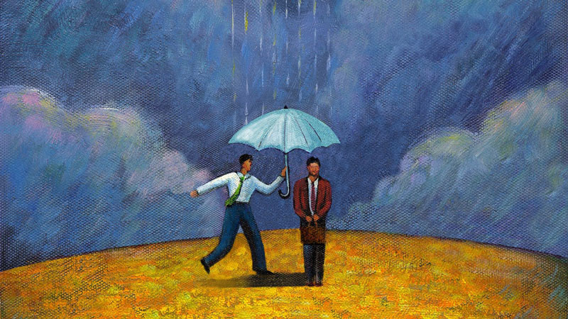 άντρας που φέρνει μία ομπρέλα σε κάποιον που στέκεται στη βροχή
