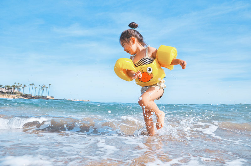παιδί με μπρατσάκια παίζει στη θάλασσα