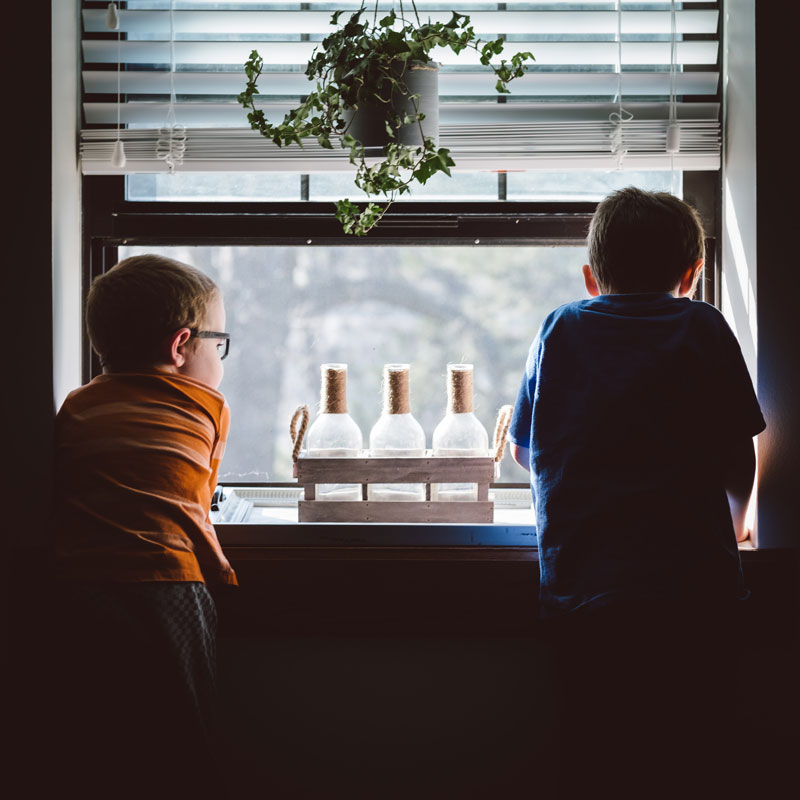 δύο αδέλφια κοιτάζουν έξω από το παράθυρο