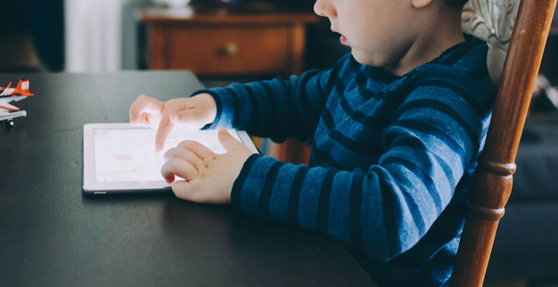 μικρό παιδί χωρίς επιτήρηση γονέα χρησιμοποιεί tablet στο τραπέζι