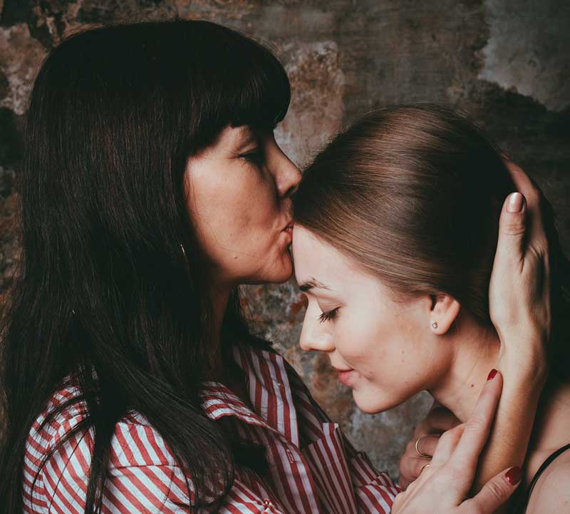 μητέρα φιλάει τη κόρη της στο μέτωπο καθώς αναζητά τη γυναικεία ταυτότητα στη σχέση μητέρας - κόρης