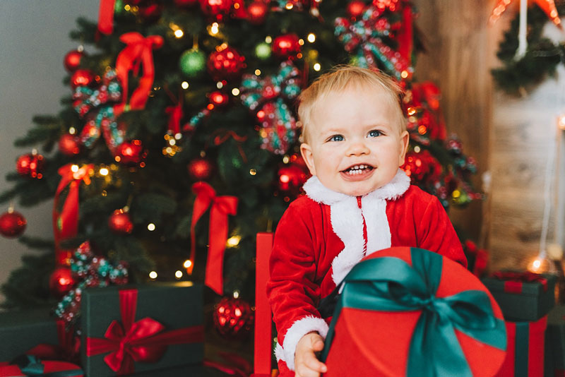 παιδί με δώρο στα χέρια μπροστά από χριστουγεννιάτικο δέντρο