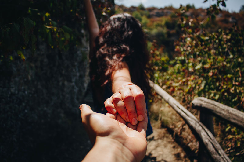 γυναίκα κρατάει το χέρι ενός αγαπημένου συντρόφου σε ένα μονοπάτι