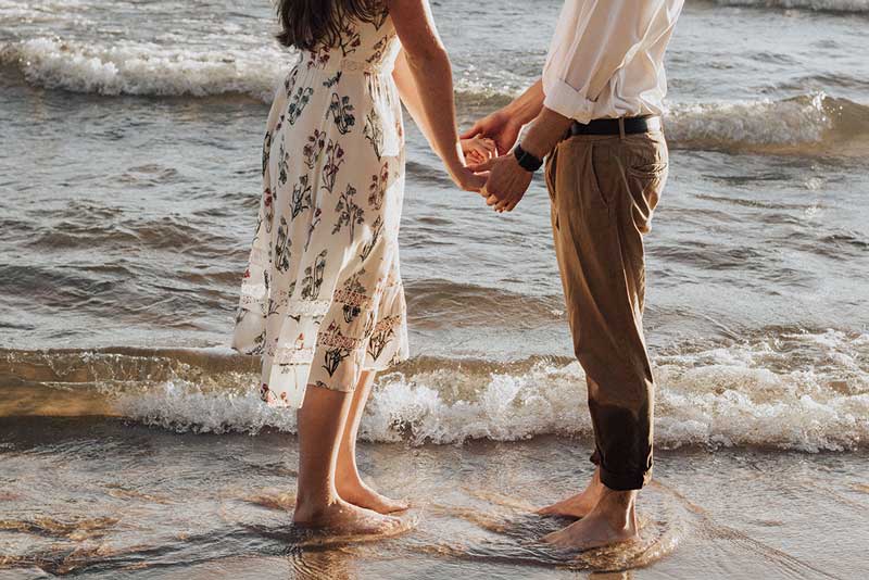 ζευγάρι που έχει στενή σχέση, περπατά στη θάλασσα κρατώντας ο ένας το χέρι του άλλου εξωτερικεύοντας την ευαλωτότητα