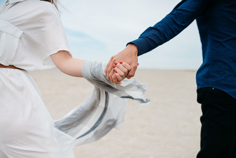 υγιές και ευτυχισμένο ζευγάρι κρατιέται χέρι-χέρι στην παραλία
