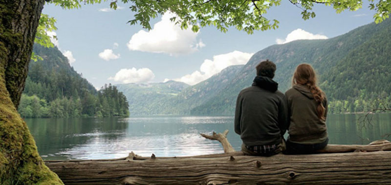 ζευγάρι καθισμένο σε κορμό δέντρου κοιτάζει τη λίμνη