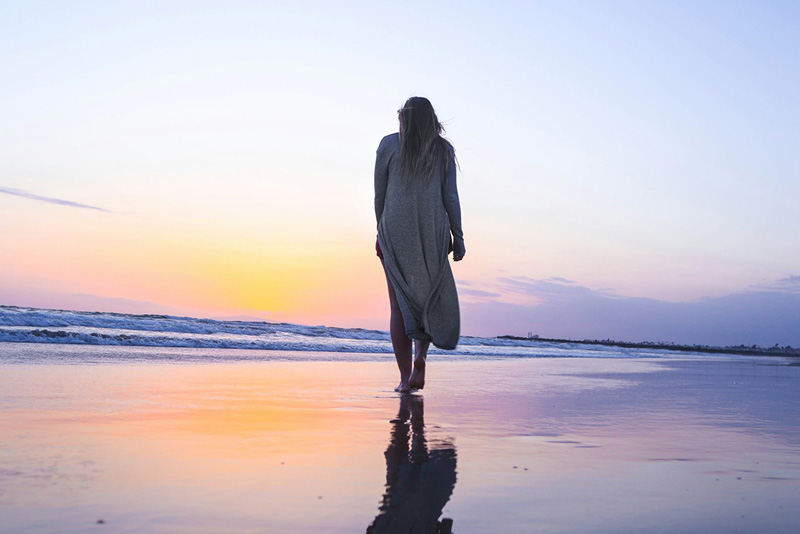 κοπέλα που βιώνει τη μοναξιά με γυρισμένη πλάτη κοιτάει τη θάλασσα επηρεάζει την ψυχική της υγεία
