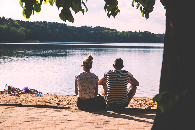 άνδρας και γυναίκα καθιστοί μπροστά από μία λίμνη