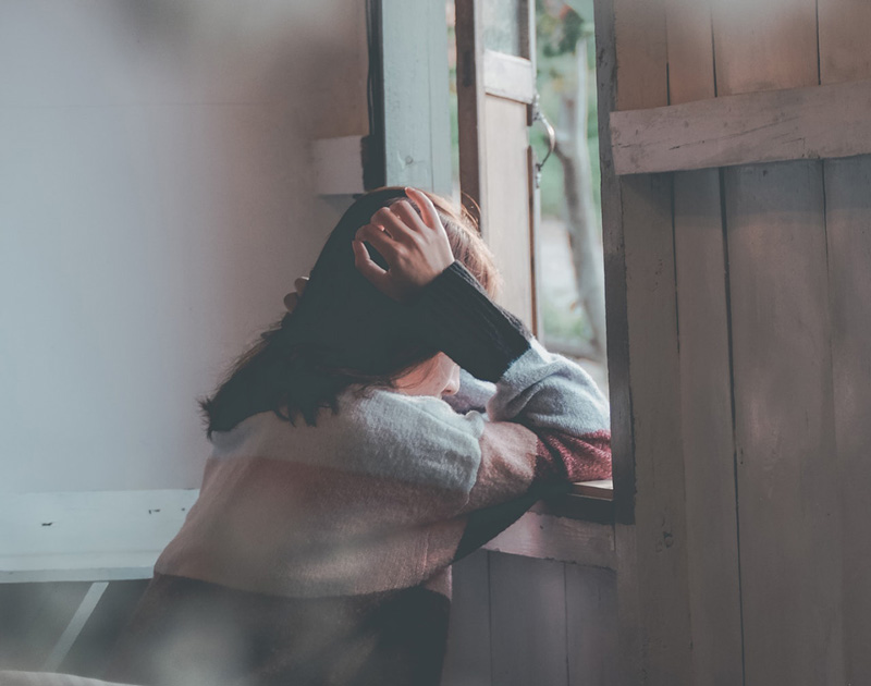 γυναίκα καθισμένη μπροστά από ένα παράθυρο θέλει ψυχική υγεία