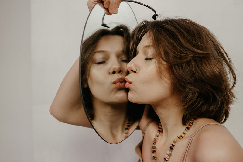 γυναίκα φιλάει τον καθρέφτη και αναρωτιέται Πώς είναι πραγματικά να έχεις σχέση με έναν ναρκισσιστή