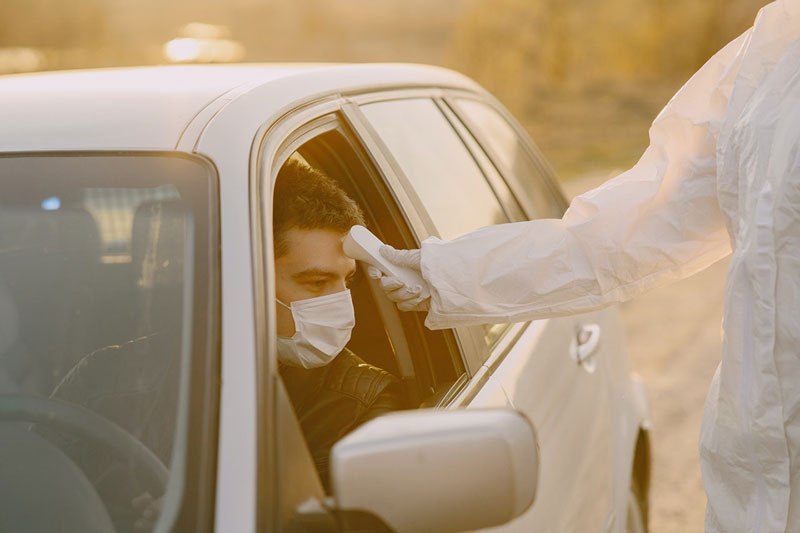 άντρας κάνει τεστ θερμοκρασίας στο αμάξι για τον Κορωνοϊό, με φόβος που προκαλεί η φονική πανδημία