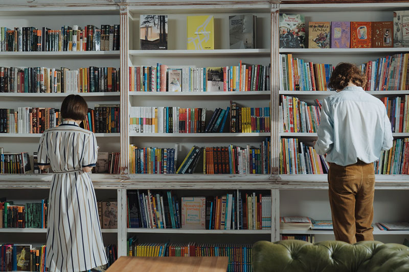 ζευγάρι διαβάζει βιβλία μπροστά από μια βιβλιοθήκη