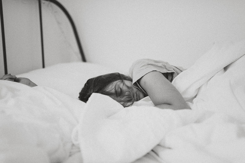 ασπρόμαυρη φωτογραφία με γυναίκα που είναι ξαπλωμένη στο κρεβάτι