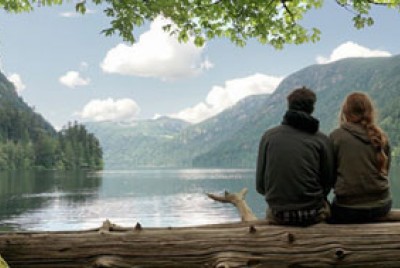 ζευγάρι καθισμένο σε κορμό δέντρου κοιτάζει τη λίμνη