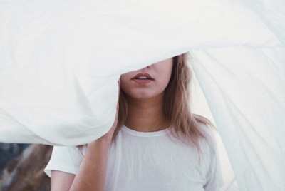 κοπέλα που κρύβεται μέσα σε ένα λευκό σεντόνι και νιώθει την ψευδαίσθηση της ελευθερίας που παρέχει η αναβλητικότητα