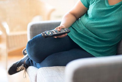 γυναίκα καθισμένη στον καναπέ βλέπει τηλεόραση