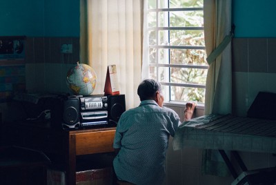 ηλικιωμένο άτομο σε καραντίνα κοιτάζει έξω από το παράθυρο