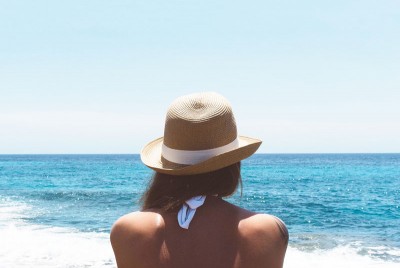 γυναίκα κάθεται στη παραλία και κοιτάζει τη θάλασσα