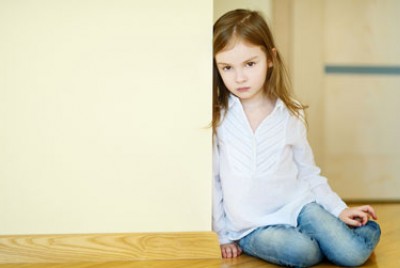 κοριτσάκι που κάθεται στο πάτωμα ακουμπισμένο σε ένα τοίχο