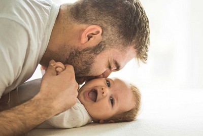 πατέρας φιλάει το μωρό ενώ αυτό γελάει