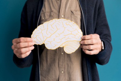 άτομο κρατάει ένα χάρτινο εγκέφαλο στα χέρια του