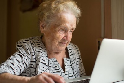 ηλικιωμένη γυναίκα χρησιμοποιεί φορητό υπολογιστή