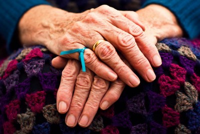 χέρια ηλικιωμένου με την γαλάζια κορδέλα για τη νόσο του Αλτσχάιμερ 