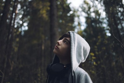 έφηβος με καστανά μαλλιά και ακουστικά στο δάσος