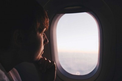 σκεπτικός άντρας που κοιτάζει μέσα από το παράθυρο ενός αεροπλάνου