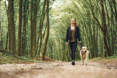 γυναίκα κάνει «Silent walking» σε δάσος με το σκύλο της