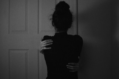 γυναίκα αγκαλιάζει τον εαυτό της και σκέφτεται ένα γράμμα στο σώμα της