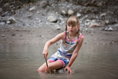 κορίτσι παίζει στην άμμο με ένα ξύλο