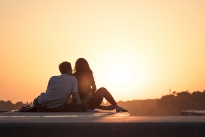 ζευγάρι καθισμένο σε μια ταράτσα βλέπει το ηλιοβασίλεμα