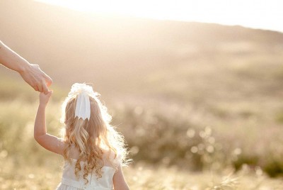 μικρό ξανθό κοριτσάκι περπατάει στη φύση κρατώντας το χέρι του γονέα της