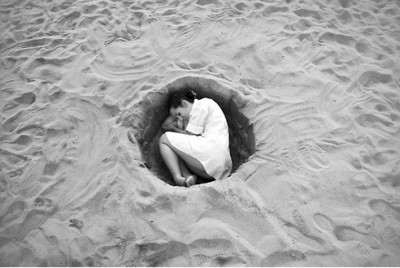 γυναίκα σε στάση εμβρύου σε ένα λάκκο στην άμμο