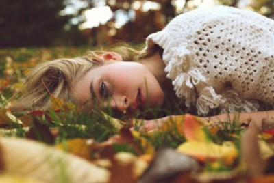 γυναίκα ξαπλωμένη σε γρασίδι γεμάτο φύλλα