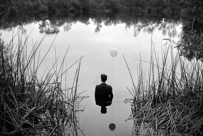 άντρας με κουστούμι μέσα σε μια λίμνη κρατάει ένα μπαλόνι