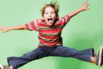 χαρούμενο παιδί πηδά στο αέρα με τα πόδια ανοιχτά