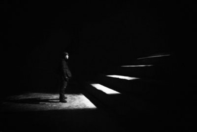 άνθρωπος στέκεται στο τέλος των σκαλοπατιών σε ένα σκοτεινό δωμάτιο