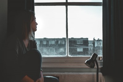 γυναίκα καθισμένη μπροστά από το παράθυρο διαχειρίζεται το άγχος και τα υπόλοιπα αρνητικά συναισθήματα