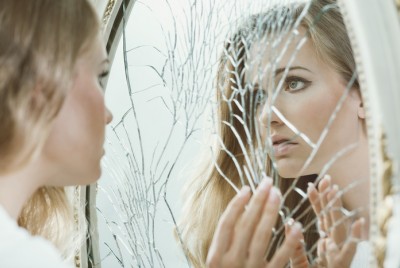 γυναίκα κοιτάζει ένα ραγισμένο καθρέπτη και πάσχει από οριακή διαταραχή προσωπικότητας