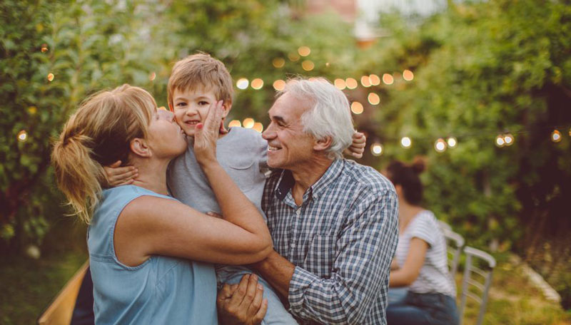 παππούς και γιαγιά φιλούν το εγγόνι τους στην εξοχή
