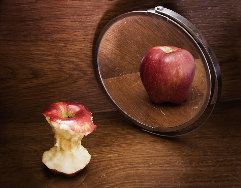 ένα φαγωμένο μήλο που όμως στον καθρέπτη φαίνεται άθικτο