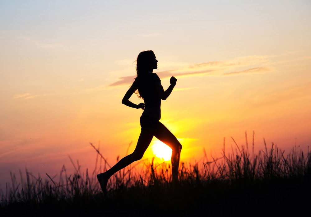 γυναίκα που τρέχει με φόντο το ηλιοβασίλεμα