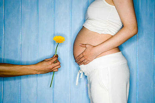 άντρας προσφέρει λουλούδι σε έγκυο γυναίκα
