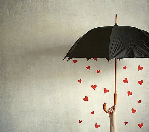 γυναίκα κρατάει ομπρέλα ενώ βρέχει καρδιές