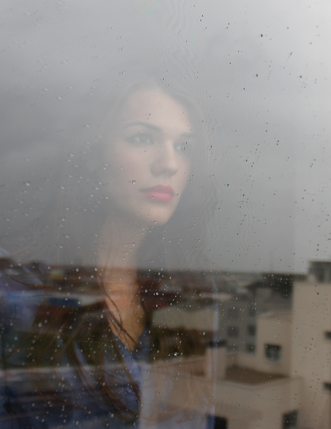 γυναίκα κοιτάζει πίσω από ένα παράθυρο έξω στη πόλη