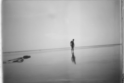 ένας άνθρωπος μόνος του σε ρηχή θάλασσα σε ασπρόμαυρη εικόνα