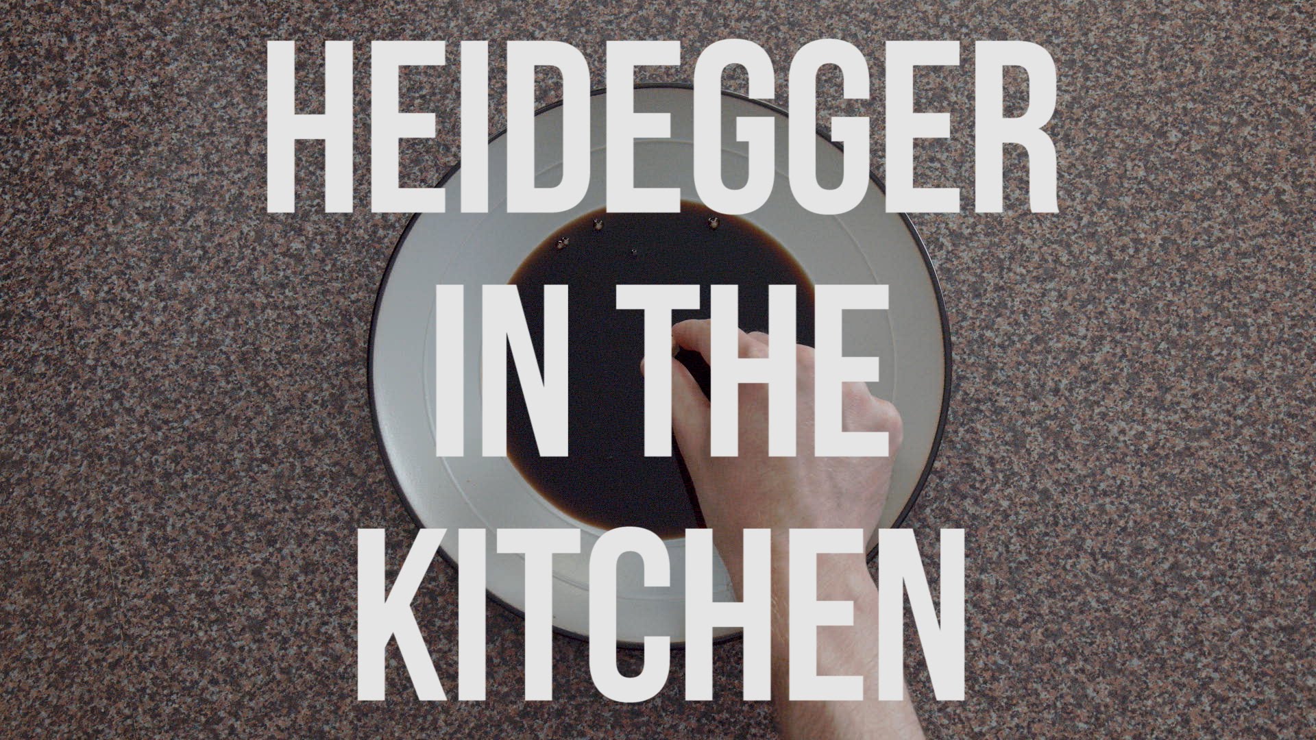 ένα χέρι πάνω από ένα πιάτο και μία επιγραφή heidegger in the kitchen